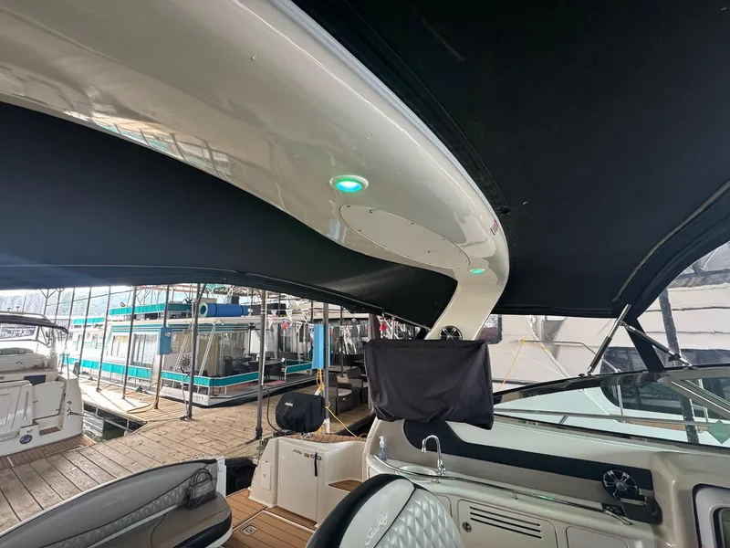Slide: The Image of 2002 Sea Ray 380 Sundancer interior with black canopy and docked boats in background. - 32