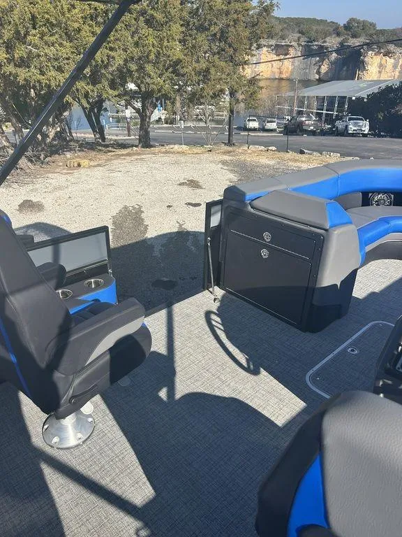 Slide: The Image of 2023 Berkshire 25UL STS 3.0 boat interior with blue and black seating, parked outdoors. - 11