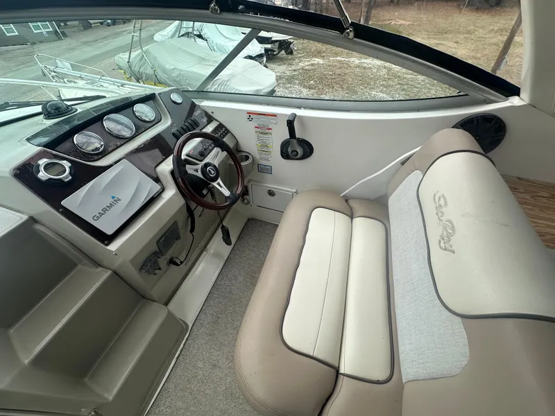 Slide: The Image of 2012 Sea Ray 280 Sundancer cockpit with steering wheel, gauges, and beige seating. - 11