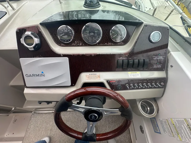 Slide: The Image of 2012 Sea Ray 280 Sundancer dashboard with Garmin navigation and wood-trimmed steering wheel. - 12