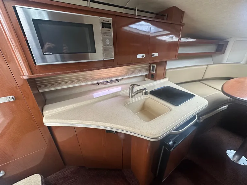 Slide: The Image of 2012 Sea Ray 280 Sundancer interior kitchen with microwave, sink, and seating area. - 15
