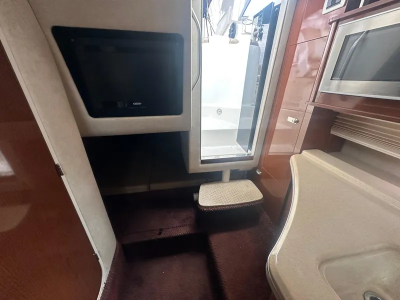 Slide: The Image of Interior of 2012 Sea Ray 280 Sundancer boat, featuring a TV and kitchenette area. - 19