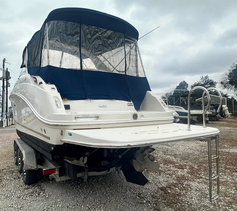 Slide: The Image of 2012 Sea Ray 280 Sundancer boat with blue canopy on trailer, overcast sky. - 2