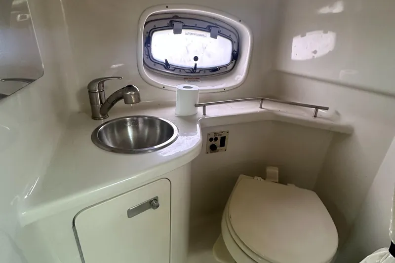 Slide: The Image of 2012 Sea Ray 280 Sundancer bathroom with sink, toilet, and porthole window. - 23