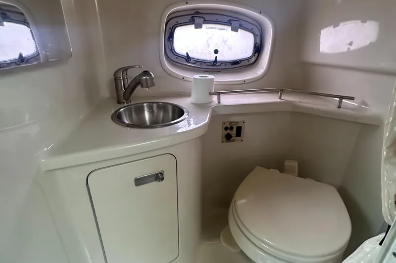 Slide: The Image of 2012 Sea Ray 280 Sundancer bathroom with sink, toilet, and porthole window. - 24
