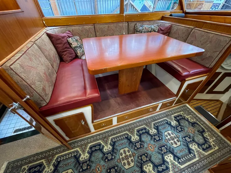 Slide: The Image of 1959 Monk Express Cruiser interior with wooden table, cushioned seating, and decorative rug. - 12