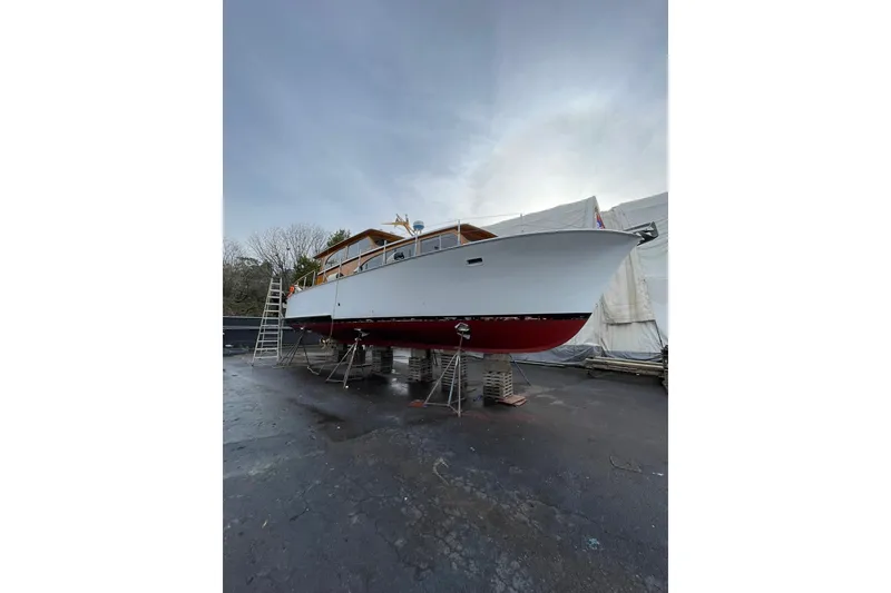 Slide: The Image of 1959 Monk Express Cruiser on dry dock, white hull with red bottom, overcast sky. - 41