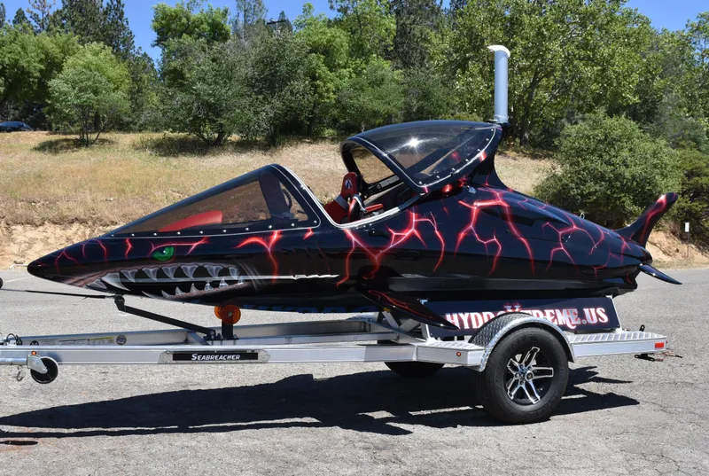 Slide: The Image of 2025 Seabreacher X, Y, Z on trailer, black with red lightning design, parked outdoors. - 14