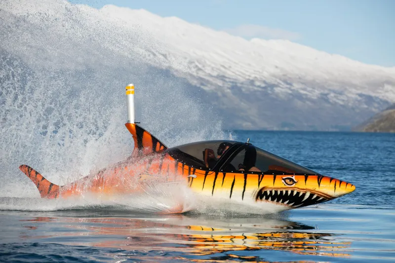 Slide: The Image of A 2025 Seabreacher X, Y, Z submersible, shark-themed, speeding on a lake with snowy mountains. - 37
