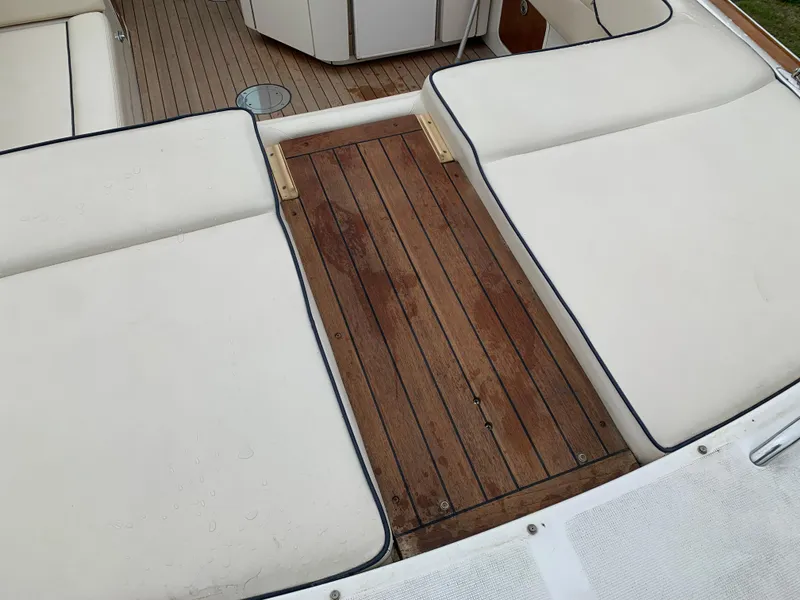 Slide: The Image of 2005 Chris-Craft Corsair 28 boat interior with wooden deck and white cushioned seating. - 11