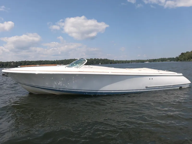 Slide: The Image of 2006 Chris-Craft Corsair 28 boat on a calm lake under a blue sky. - 32