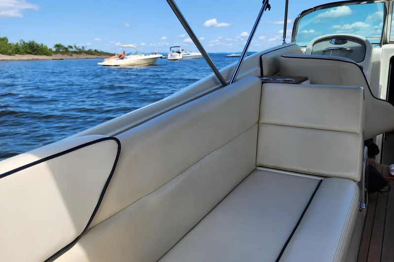 Slide: The Image of 2006 Chris-Craft Corsair 28 boat interior with beige seating, on a sunny day by the water. - 48