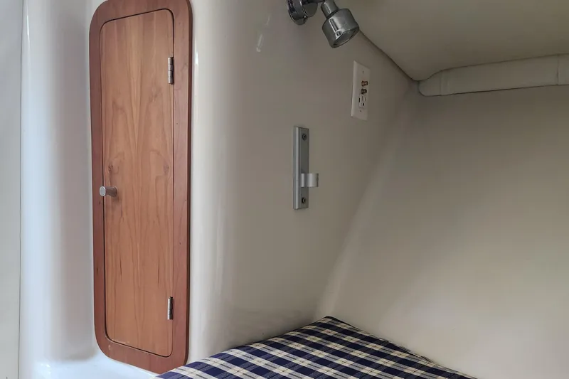Slide: The Image of Interior cabin of 2006 Chris-Craft Corsair 28 with wooden door and plaid bedding. - 53