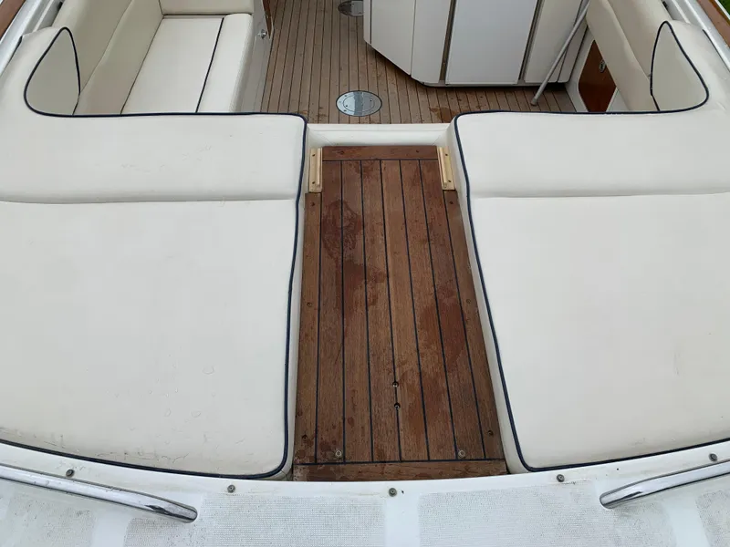 Slide: The Image of 2005 Chris-Craft Corsair 28 boat interior with white cushioned seating and wooden deck. - 9