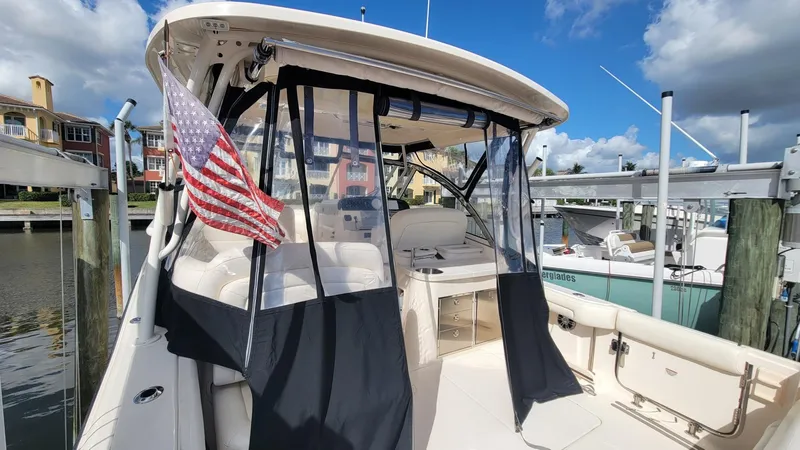 Slide: The Image of 2021 Grady-White Freedom 335 boat docked, featuring American flag and clear weather enclosure. - 11