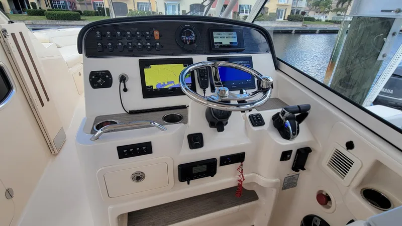 Slide: The Image of 2021 Grady-White Freedom 335 boat dashboard with steering wheel and navigation controls. - 17
