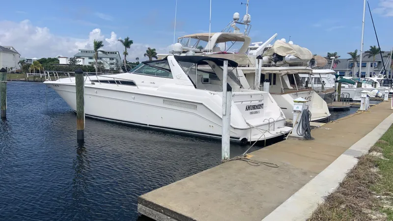 The Image of 1994 Sea Ray 500 Sundancer yacht docked at marina, clear sky, calm water. - 0