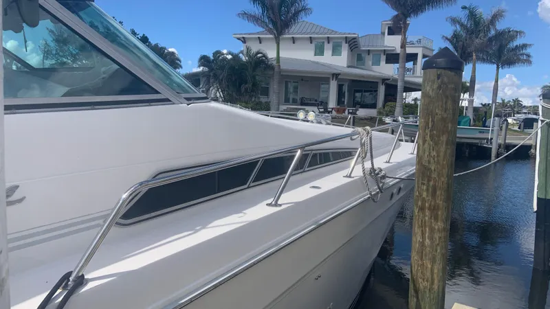 Slide: The Image of 1994 Sea Ray 500 Sundancer yacht docked near waterfront home with palm trees. - 5