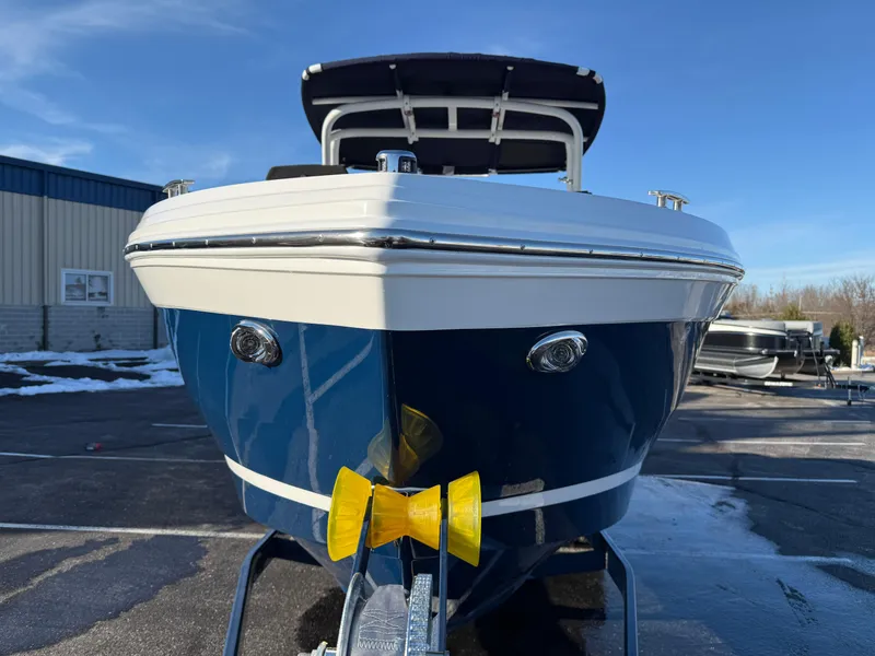 Slide: The Image of 2025 Cobalt R6 Surf boat, blue and white, parked outdoors on a sunny day. - 11