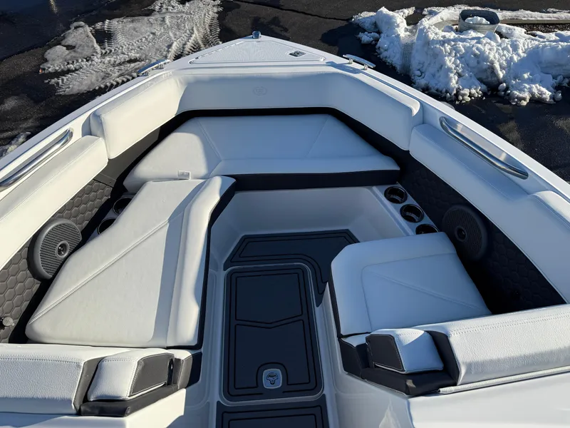 Slide: The Image of 2025 Cobalt R6 Surf boat interior with white seating and black accents, parked near snow. - 29