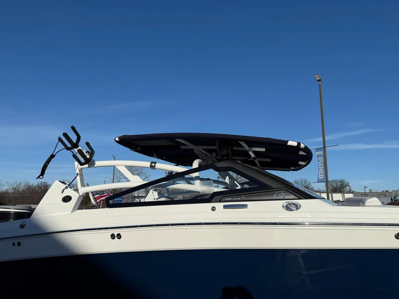 Slide: The Image of 2025 Cobalt R6 Surf boat with wakeboard rack under clear blue sky. - 47