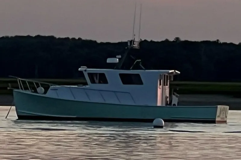 Slide: The Image of Young Brothers 40 boat from 1988 on calm water at sunset. - 3