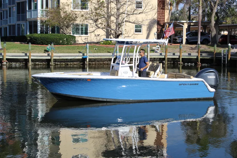 Slide: The Image of 2023 Sportsman Heritage 231 Center Console boat on calm water near docks. - 2