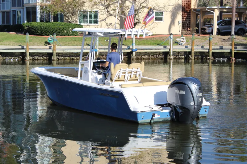 Slide: The Image of 2023 Sportsman Heritage 231 Center Console boat on water, rear view, with flags. - 6