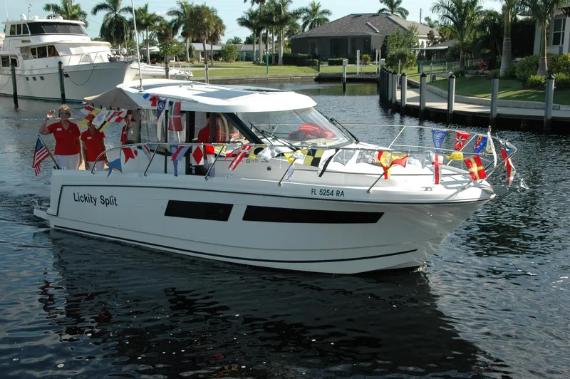 Slide: The Image of 2016 Jeanneau Merry Fisher 855 boat decorated with flags, cruising in a marina. - 0