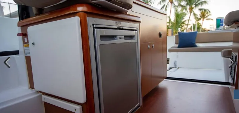 Slide: The Image of Interior of 2016 Jeanneau Merry Fisher 855, featuring compact kitchen area with fridge and cabinets. - 14