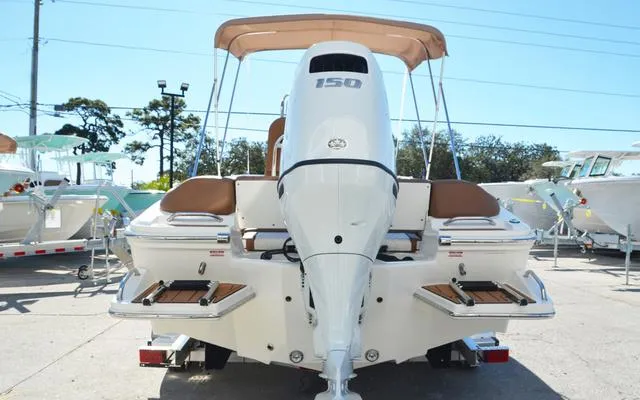 Slide: The Image of 2025 Pioneer 202 Islander boat with outboard motor, rear view, parked outdoors. - 7