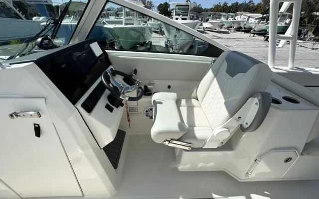 Slide: The Image of 2025 Sailfish 276 DC boat cockpit with steering wheel and white captain's chair. - 25