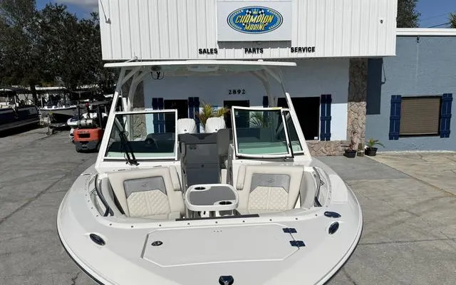 Slide: The Image of 2025 Sailfish 276 DC boat at dealership, front view, white exterior, Champion Marine sign. - 45