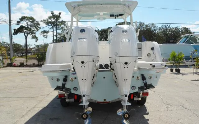 Slide: The Image of 2025 Sailfish 276 DC boat with dual outboard engines, parked outdoors. - 6