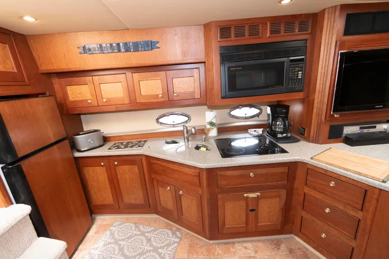 Slide: The Image of Luxurious 2003 Cruisers Yachts 5370 Express kitchen with wood cabinetry and modern appliances. - 11