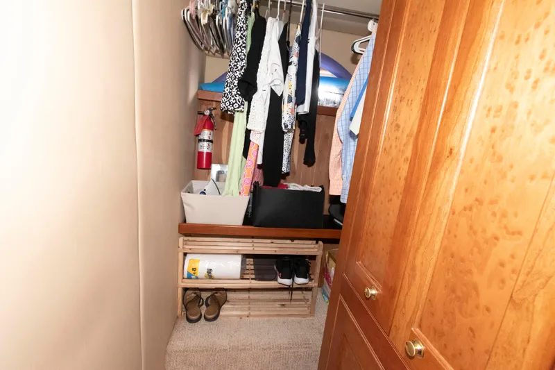 Slide: The Image of Closet in 2003 Cruisers Yachts 5370 Express with clothes, fire extinguisher, and wooden shelves. - 18