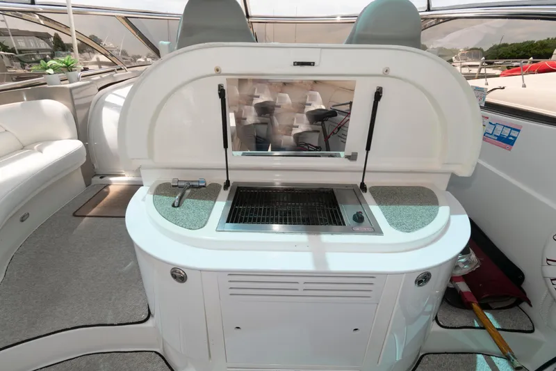 Slide: The Image of 2003 Cruisers Yachts 5370 Express boat interior with built-in grill and seating area. - 5