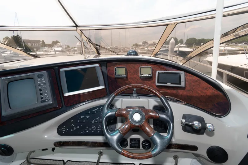 Slide: The Image of 2003 Cruisers Yachts 5370 Express helm with modern navigation equipment and wood-accented steering wheel. - 8