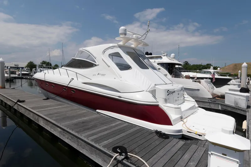 The Image of 2003 Cruisers Yachts 5370 Express docked at marina, featuring sleek design and red hull. - 0