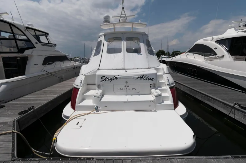 Slide: The Image of 2003 Cruisers Yachts 5370 Express docked, rear view, with "Stayin' Alive" nameplate. - 2
