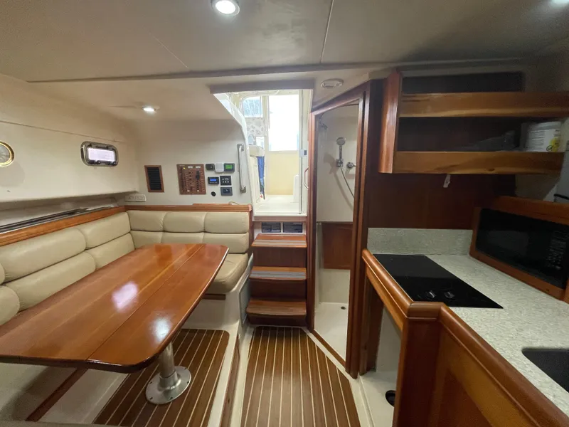 Slide: The Image of 2006 Mainship Pilot 34 interior with dining area, kitchenette, and wooden finishes. - 24