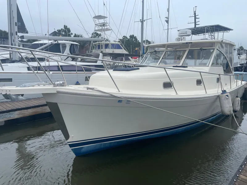 Slide: The Image of 2006 Mainship Pilot 34 boat docked in marina, featuring sleek design and white hull. - 3