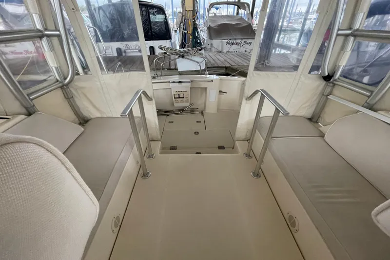Slide: The Image of 2006 Mainship Pilot 34 interior with beige seating and metal railings in a marina setting. - 37