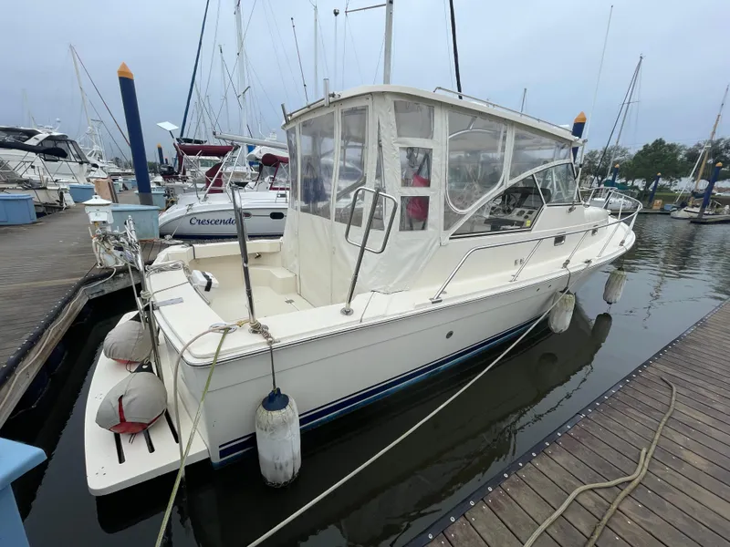 Slide: The Image of 2006 Mainship Pilot 34 docked at marina, featuring enclosed cabin and fenders. - 5