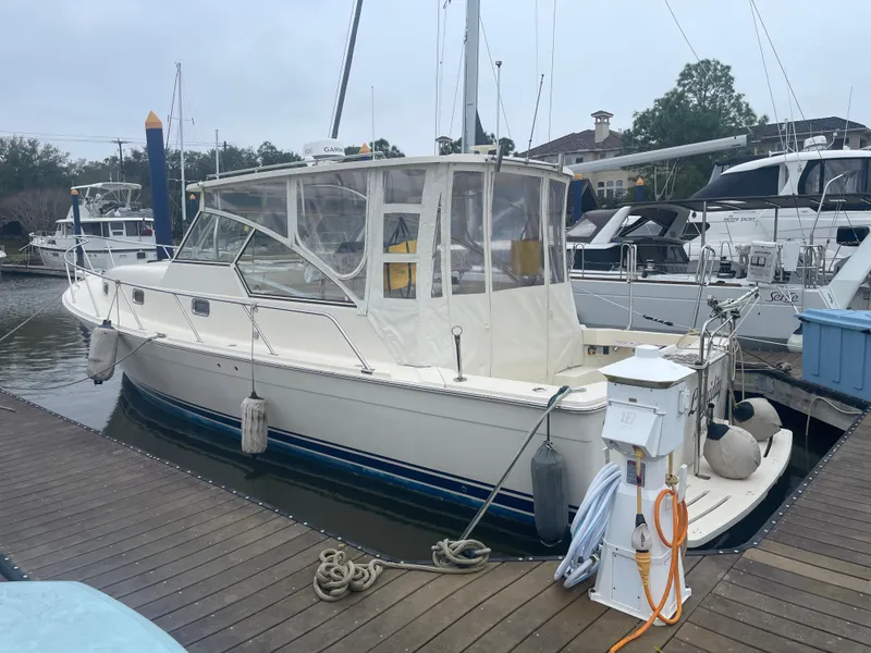 Slide: The Image of 2006 Mainship Pilot 34 docked at marina, featuring classic design and enclosed cockpit. - 7