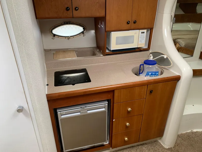 Slide: The Image of 1995 Silverton 310 Express boat kitchen with sink, microwave, and mini fridge. - 10
