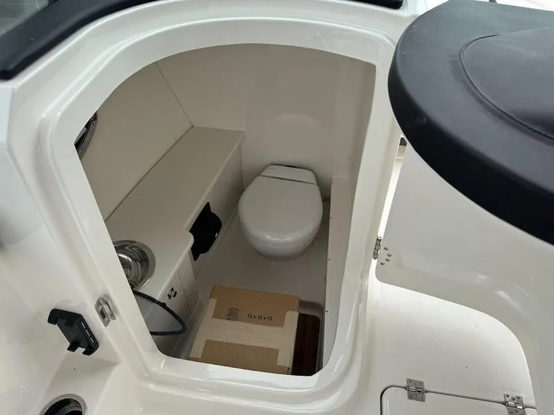 Slide: The Image of 2025 Robalo R 257 boat interior with compact marine toilet and storage space. - 9