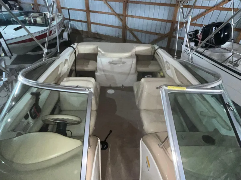 Slide: The Image of 2000 Sea Ray 185 Bow Rider interior with beige seating, stored in a boat shed. - 11