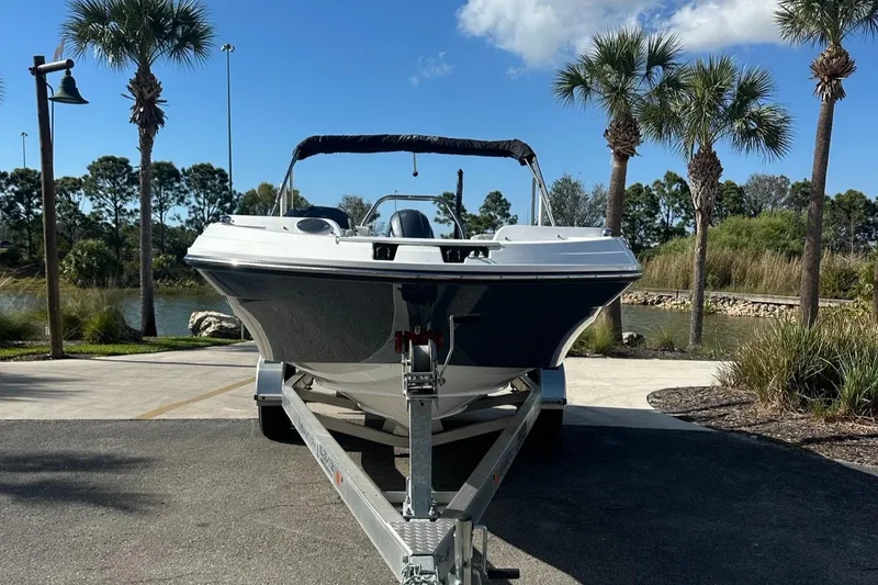 Slide: The Image of 2023 Hurricane SunDeck Sport 205 OB boat on trailer, surrounded by palm trees. - 2