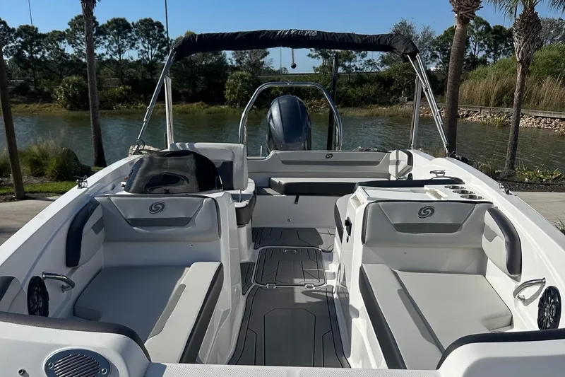 Slide: The Image of 2023 Hurricane SunDeck Sport 205 OB boat interior with seating and steering, near a scenic waterway. - 3